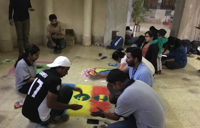 Students drawing a rangoli in a campus corridor during a festival